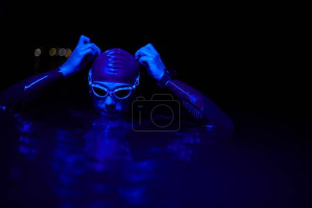 Photo for Authentic triathlete swimmer having a break during hard training on night neon gel light - Royalty Free Image