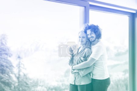 Photo for Young couple enjoying morning coffee by the window - Royalty Free Image