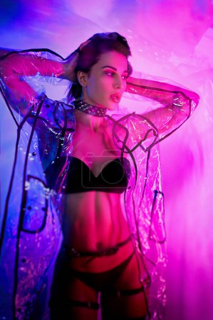 Photo for Slender woman in a swimsuit and a transparent raincoat in neon light - Royalty Free Image