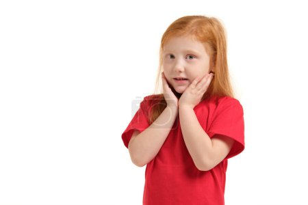 Photo for Pleasant cute upbeat little girl holding her hands near face and smiling while expressing joy. - Royalty Free Image
