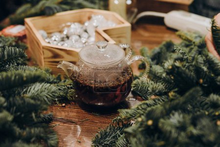 Photo for Master class on creating a Christmas wreath. Glass kettle with delicious brewed tea. - Royalty Free Image