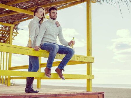 Téléchargez les photos : Jeune couple boire de la bière ensemble à la plage - en image libre de droit