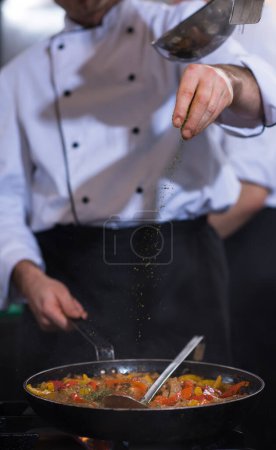 Photo for "chef putting spices on vegetables in wok" - Royalty Free Image