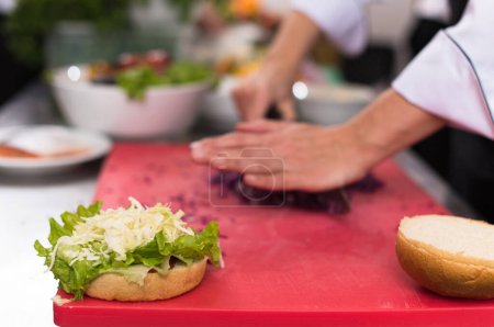 Téléchargez les photos : "chef hands cutting salad for burger" - en image libre de droit