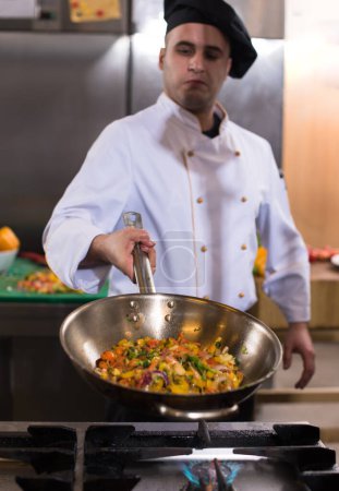Foto de "chef voltear verduras en wok" - Imagen libre de derechos