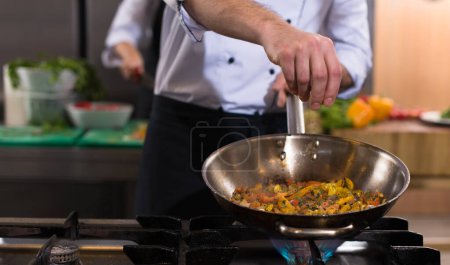 Photo for "chef putting spices on vegetables in wok" - Royalty Free Image