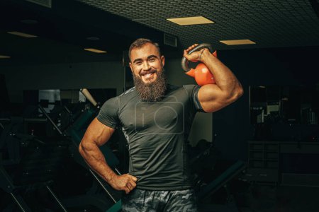 Téléchargez les photos : "Bodybuilder faire des exercices avec haltères dans une salle de gym sombre" - en image libre de droit