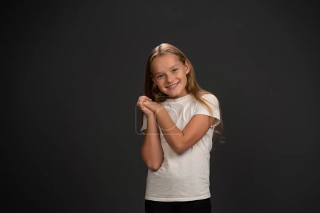 Téléchargez les photos : Agréablement heureuse petite fille inspirée par le projet scolaire avec les mains mises ensemble - en image libre de droit