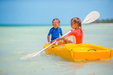 Foto de Niñas adorables disfrutando de kayak en kayak amarillo - Imagen libre de derechos