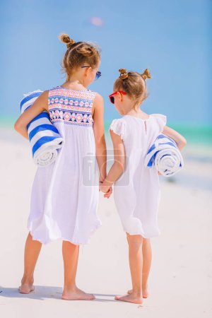 Photo for Adorable little girls with beach towels on white tropical beach - Royalty Free Image