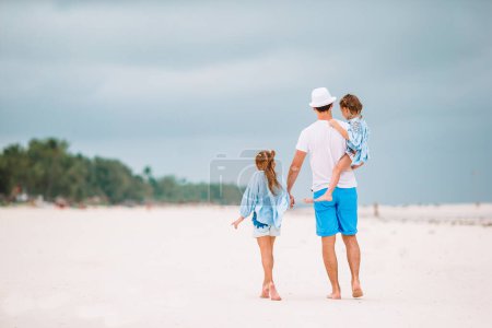 Foto de Feliz hermosa familia de papá y niños en la playa blanca - Imagen libre de derechos