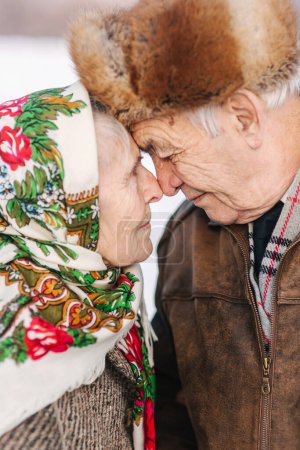 Photo for "Portrait of happy senior couple. Elderly woman kiss her husband in weighty. old couple walking in the park in winter time. Happy family. Gold wedding" - Royalty Free Image