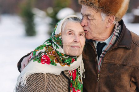 Téléchargez les photos : Portrait de couple de personnes âgées. Homme âgé embrasser sa femme dans le poids. vieux couple marchant dans le parc en hiver. Bonne famille. Mariage d'or - en image libre de droit