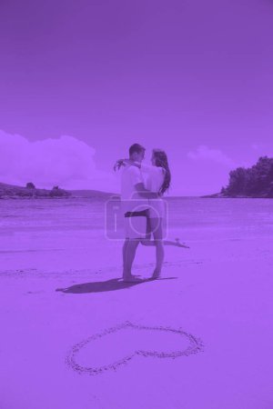 Téléchargez les photos : Couple romantique amoureux s'amuser sur la plage avec coeur dessin sur sable - en image libre de droit