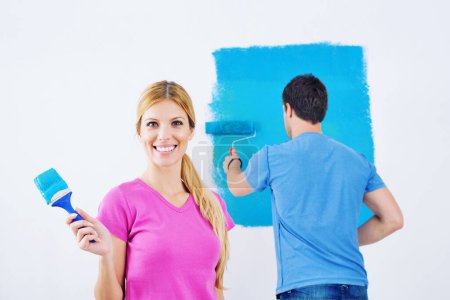 Téléchargez les photos : Jeune couple mur de peinture à la nouvelle maison - en image libre de droit