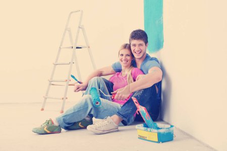 Téléchargez les photos : Heureux jeunes gens se détendre après avoir peint dans une nouvelle maison - en image libre de droit