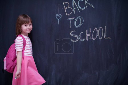 Photo for School girl child with backpack writing  chalkboard - Royalty Free Image