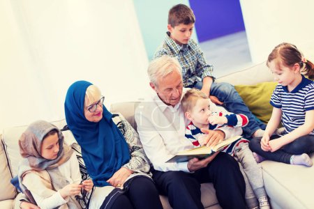 Foto de Abuelos musulmanes modernos con nietos leyendo el Corán - Imagen libre de derechos