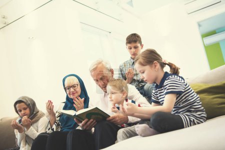 Foto de Abuelos musulmanes modernos con nietos leyendo el Corán - Imagen libre de derechos