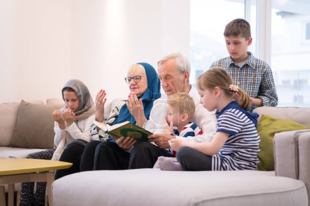 Téléchargez les photos : Grands-parents musulmans modernes avec petits-enfants lisant le Coran - en image libre de droit