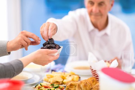 Photo for Modern multiethnic muslim family sharing a bowl of dates - Royalty Free Image
