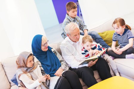 Photo for Modern muslim grandparents with grandchildren reading Quran - Royalty Free Image