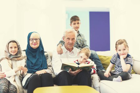 Téléchargez les photos : Grands-parents musulmans modernes avec petits-enfants lisant le Coran - en image libre de droit