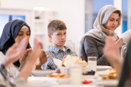 Téléchargez les photos : Famille musulmane multiethnique moderne priant avant d'avoir iftar dîner - en image libre de droit