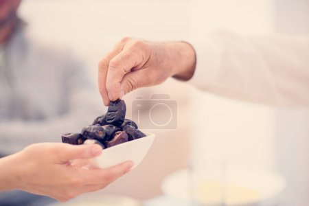 Photo for Modern multiethnic muslim family sharing a bowl of dates - Royalty Free Image