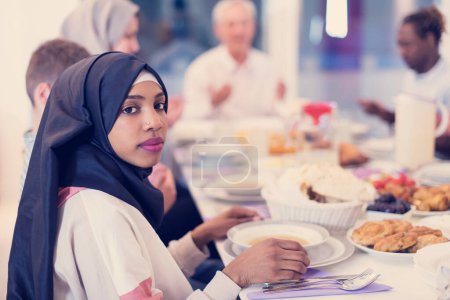 Téléchargez les photos : Noir moderne musulman femme profiter iftar dîner avec la famille - en image libre de droit