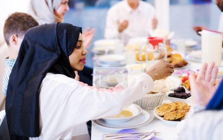 Téléchargez les photos : Noir moderne musulman femme profiter iftar dîner avec la famille - en image libre de droit