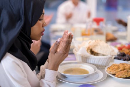 Téléchargez les photos : Femme musulmane noire moderne priant avant d'avoir iftar dîner - en image libre de droit