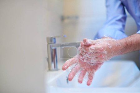 Foto de Coronavirus male wahing hands in bathroom - Imagen libre de derechos