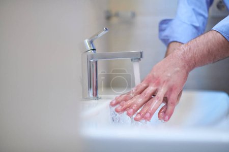 Foto de Coronavirus male wahing hands in bathroom - Imagen libre de derechos