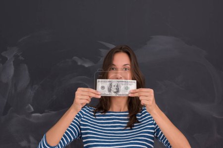 Photo for Woman holding a banknote in front of chalk drawing board - Royalty Free Image