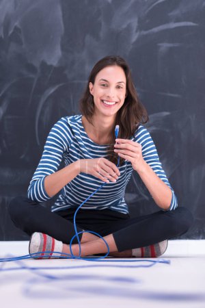 Photo for Woman holding a internet cable in front of chalk drawing board - Royalty Free Image