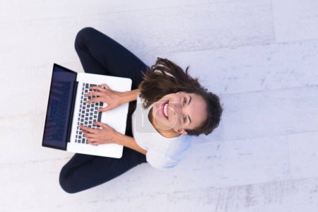 Téléchargez les photos : Femme utilisant un ordinateur portable sur la vue du dessus du sol - en image libre de droit