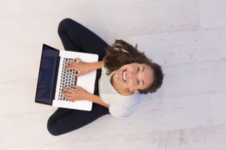 Téléchargez les photos : Femme utilisant un ordinateur portable sur la vue du dessus du sol - en image libre de droit