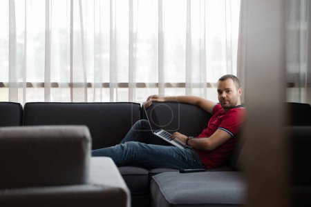 Téléchargez les photos : Homme utilisant un ordinateur portable dans le salon - en image libre de droit