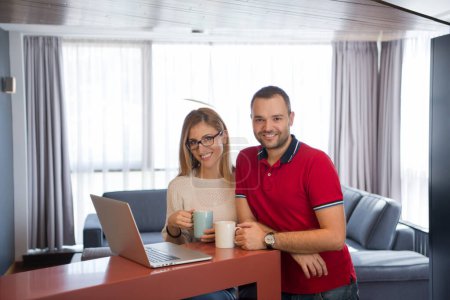 Téléchargez les photos : "couple boire du café et en utilisant un ordinateur portable à la maison
" - en image libre de droit