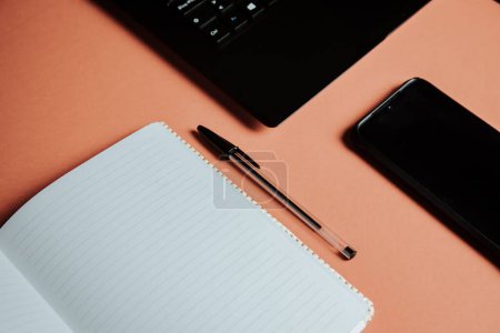 Foto de Blank notepad is on top of color office desk table with laptop computer, phone and supplies. Top view with copy space, flat lay. Minimal concept, work space - Imagen libre de derechos