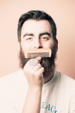 Téléchargez les photos : "Portrait of bearded barber holding equipments in hand, looking at camera, isolated on pastel background" - en image libre de droit