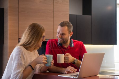 Téléchargez les photos : "couple boire du café et en utilisant un ordinateur portable à la maison
" - en image libre de droit