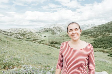 Photo for "Portrait of a young woman in the Picturesque summer landscape of highland Beautiful landscape with mountains. Viewpoint panorama in Lagos de Covadonga, Picos de Europa National Park, Asturias, Spain" - Royalty Free Image
