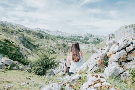Photo for "Young woman sitting resting on the mountains after a travel day. Idyllic scenario views of the spanish mountains. Resting after a day of walking copy space for add" - Royalty Free Image