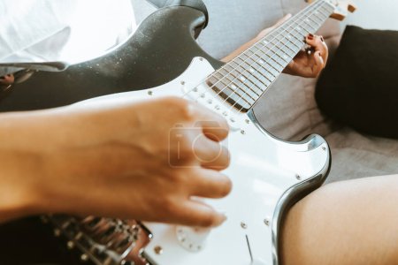 Photo for "Close up of a young woman pair of hands playing a guitar outdoors. Sunny day and practicing an instrument concept. Copy space music life on tour and nature." - Royalty Free Image