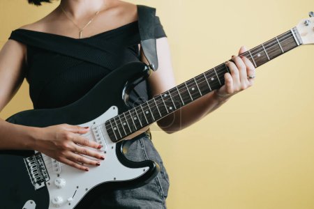 Téléchargez les photos : Image de studio conceptuelle d'une femme jouant de la guitare électrique, fond jaune, fond amovible, conception de bannières, publicité sur les réseaux sociaux, espace de copie - en image libre de droit