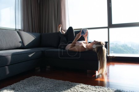 Foto de Preciosa mujer rubia escuchando música mientras descansa en el sofá - Imagen libre de derechos