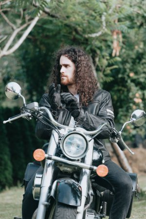 Foto de Portrait of a young long hair man, an old biker in a leather jacket on a retro bike, vintage classic motorcycle. concept of freedom and style, a hobby for life. copy space - Imagen libre de derechos