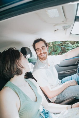 Téléchargez les photos : Lovely young couple traveling doing a road trip in car. Road travel, frontal portrait smiling. Hipster modern couple watching each other. - en image libre de droit